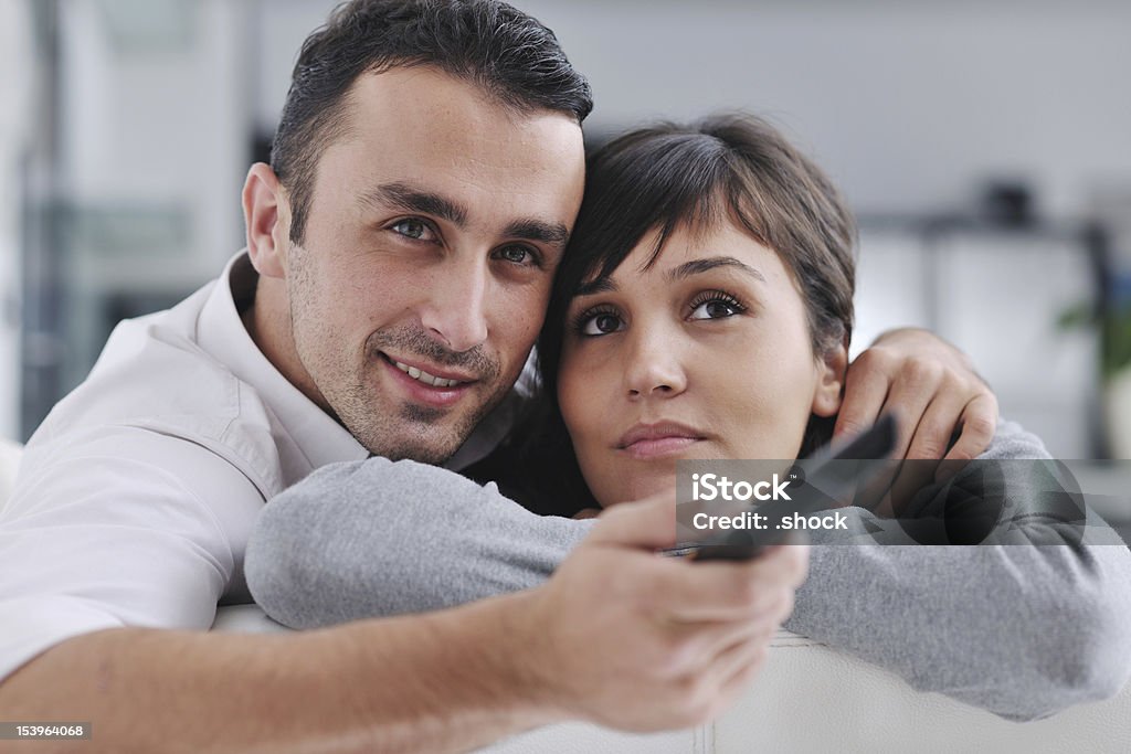 Relaxed young  couple watching tv at home Relaxed young  couple watching tv at home in bright living room Adult Stock Photo