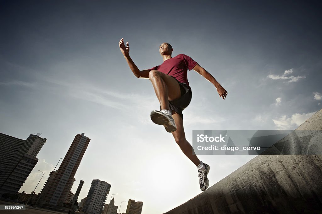 hispanic man running and jumping from a wall Latin american athlete running in Havana, Cuba. Horizontal shape, full length, low angle view Low Angle View Stock Photo