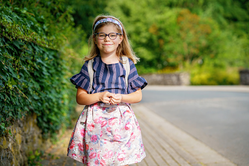 Little Preschool Girl on the Way to School. Healthy Happy Child Walking to Nursery School and Kindergarten. Smiling Child with Eyeglasses and Backpack on the City Street, Outdoors. Back to School