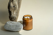 Scented candle in a brown glass jar on wood texture. Home decor, aroma therapy rest relaxation meditation.