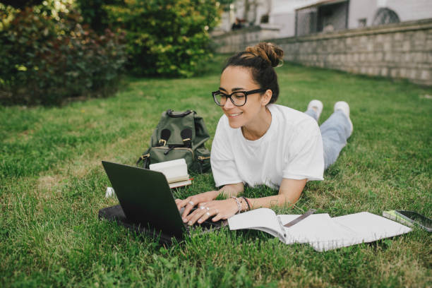 istock Young woman student studying using her books, laptop and notebook, sitting on grass. 1539721945