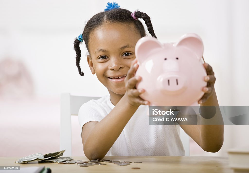 Responsável garota colocando dinheiro na piggy bank para a economia futura - Foto de stock de Cofre de porquinho royalty-free