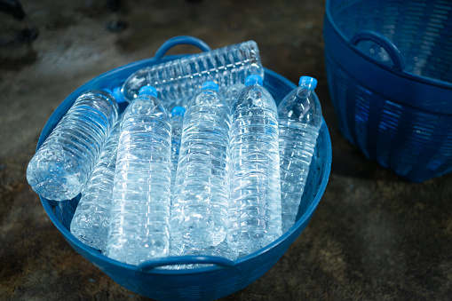 Plastic bottles of drinking water in a blue plastic basket on the floor