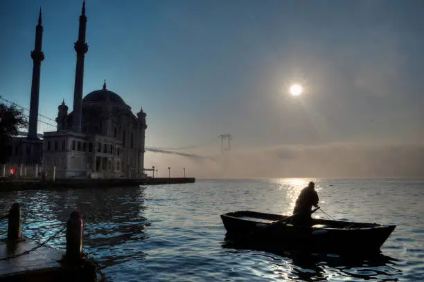 Bosphorus Bridge, Ortakoy Mosque and Fisherman in foggy morning Istanbul Turkey