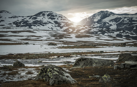 Picturesque Panorama of Rising Sun Coming Up Between Hills of Snowy Mountains. Beautiful Norwegian Landscape.