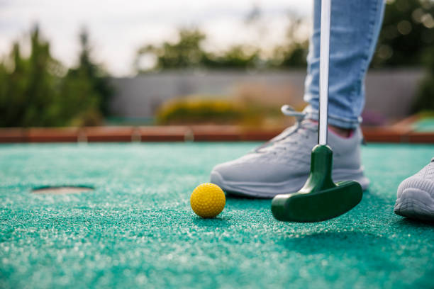 istock Golfer playing mini golf and trying putting ball into hole 1539737380