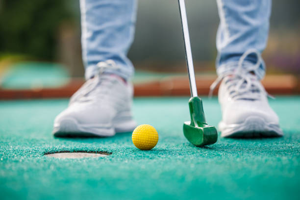 Golfer playing miniature golf and trying putting ball into hole