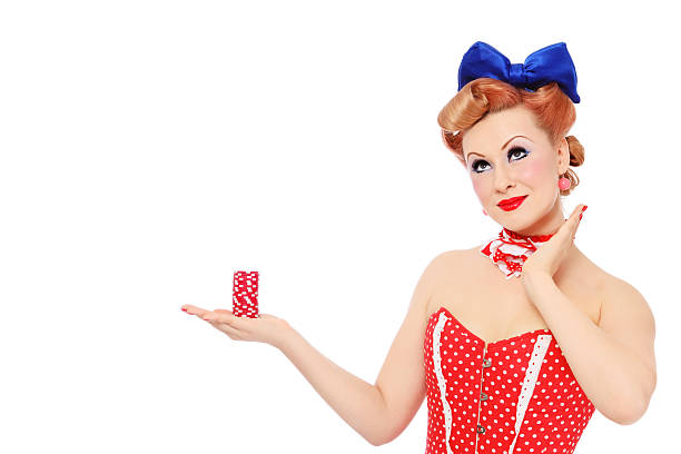Girl with poker chips Young beautiful promo pin-up girl in vintage polka dot corset with red dice in hand over white background, copy space 40s pin up girls stock pictures, royalty-free photos & images