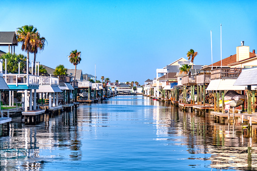 Galveston, United States - June 12, 2022:  Homes on stilts along a canal on the Gulf of Mexico on Galveston Island Texas on an early summer afternoon.