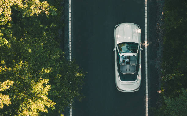 Aerial View of White Convertible Car on a Road Aerial View of Man Driving His Modern White Cabriolet Along the Road. Luxury Lifestyle Theme. convertible car top view stock pictures, royalty-free photos & images