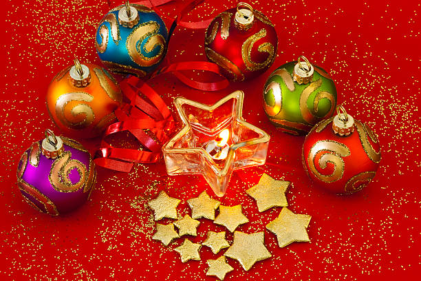 weihnachten kugeln und sternförmigen brennenden kerze auf rotem hintergrund - candle heat gold burning stock-fotos und bilder