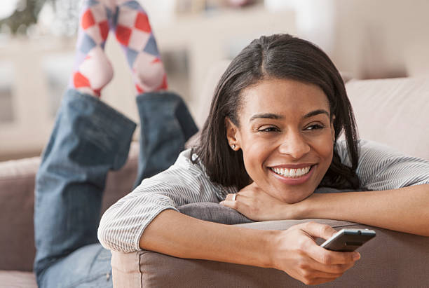 istock Young woman holding remote control smiling 153977827