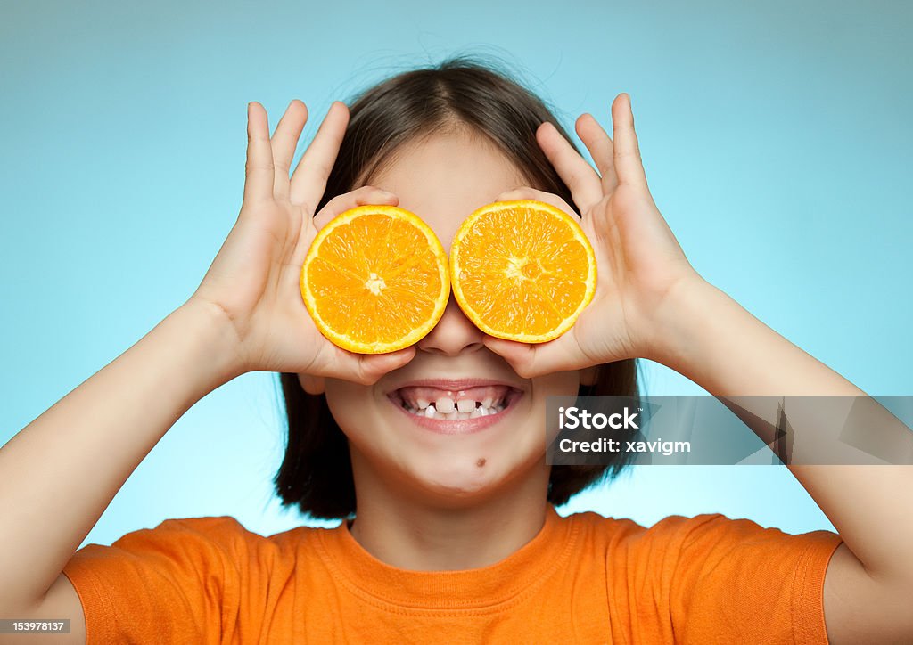 little girl using oranges as glasses little girl using oranges as glasses on a blue background Beauty In Nature Stock Photo