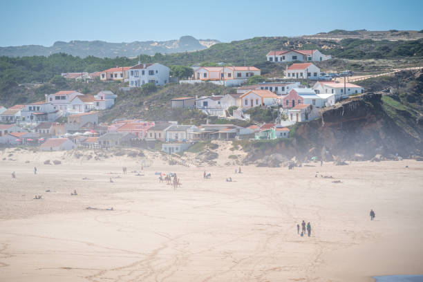 October 20, 2020 - Aljezur, Portugal: view of Monte Clerigo sandy beach, people sunbathing and walking in the sand, sunshine weather at atlantic ocean coast, Aljezur, Algarve, Portugal