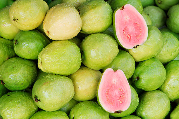A photo of fresh red guavas, a typical tropical fruit Fresh guavas with pink flesh being sold in a Vietnamese market guava photos stock pictures, royalty-free photos & images