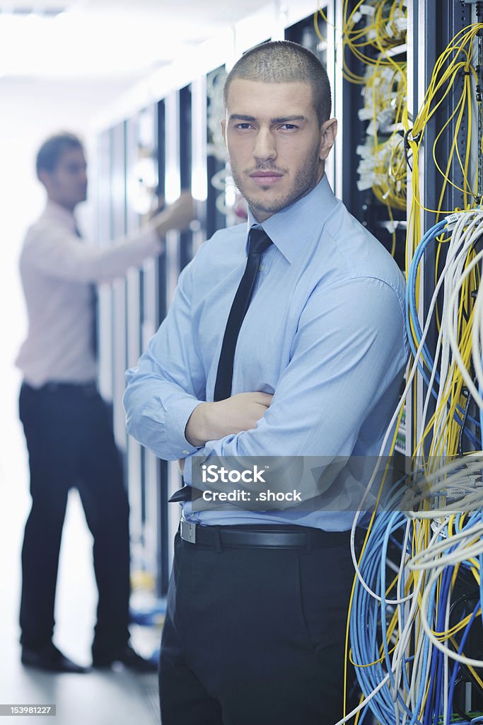 Ele engenheiros na sala de servidores de rede - Foto de stock de Assistência royalty-free
