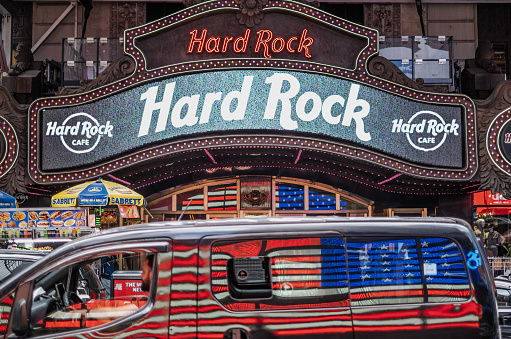 (IPTC format photo metadata added to file for press use) View from Time Square. A van driving next to Hard Rock Cafe and National flag's reflection shining on it.