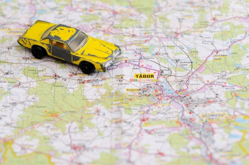Old miniature model of retro yellow car placed on map.