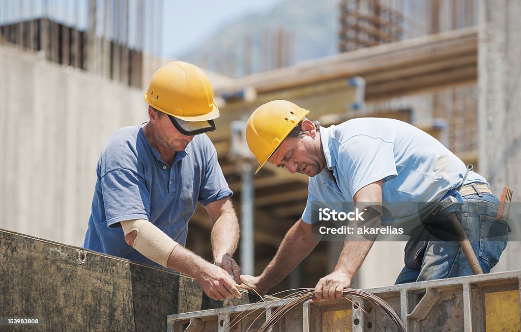 Construction workers working on cement formwork frames Authentic construction workers collaborating in the installation of cement formwork frames Construction Worker Stock Photo