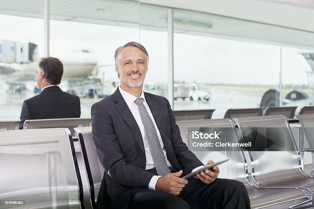 Retrato de empresario sonriente sosteniendo digital tablet en el aeropuerto - Foto de stock de 45-49 años libre de derechos