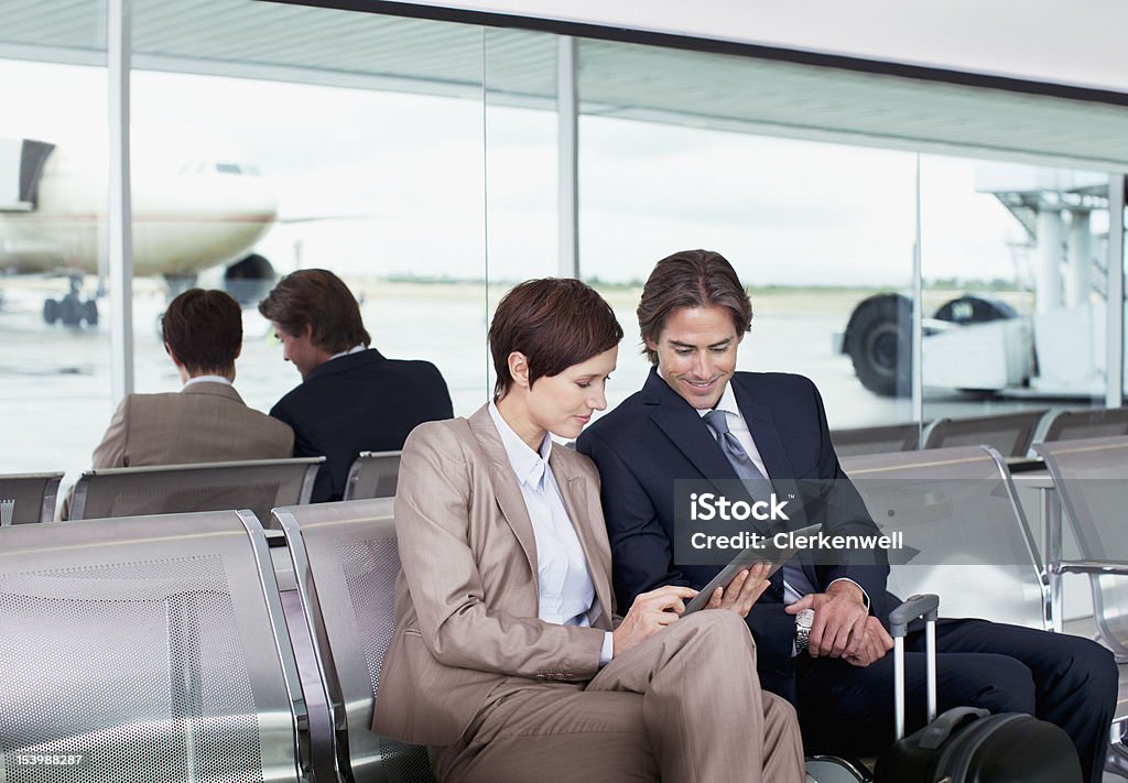 Empresario y empresaria usando tableta digital en el aeropuerto - Foto de stock de Aeropuerto libre de derechos