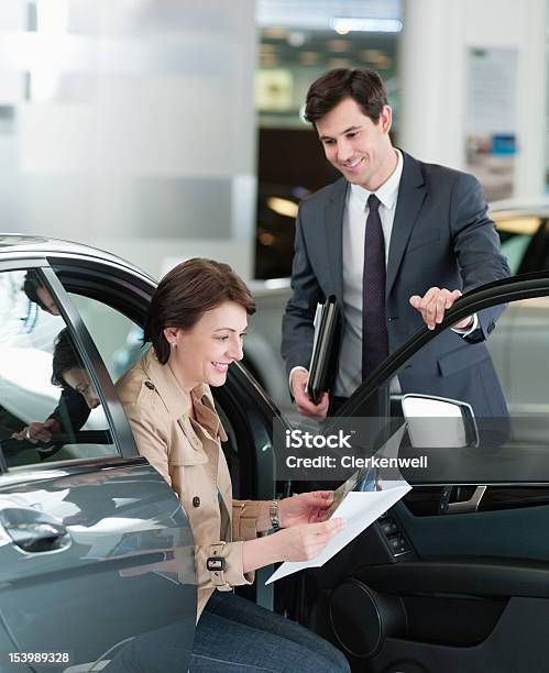 Venditore Guardare Donna Guardando Brochure In Concessionaria Sh - Fotografie stock e altre immagini di Venditore di automobili