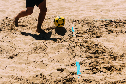 Close up of unidentifiable man playing Footvolley on the beach on a sunny summer day