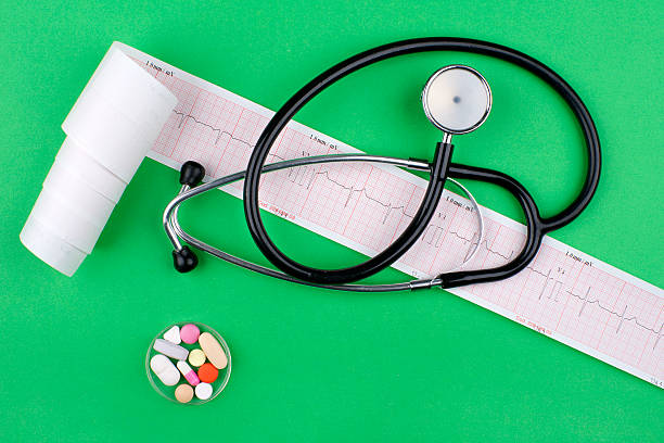 stethoscope, ECG and pills on green  background stock photo