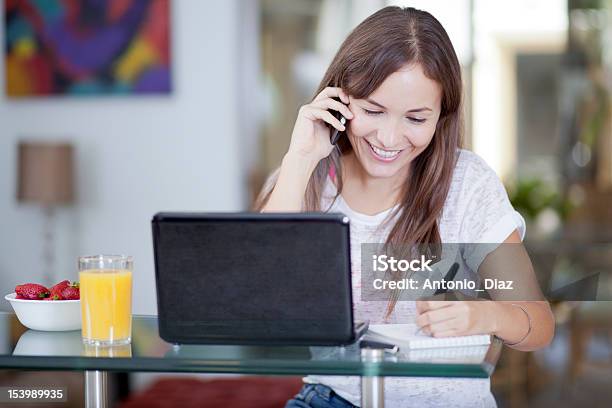 A Cute Woman Working On Her Laptop And Using The Phone Stock Photo - Download Image Now