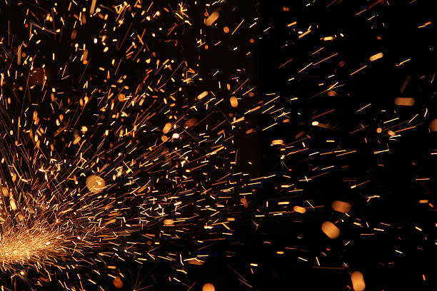 Up close photo of welding sparks flying through darkness stock photo
