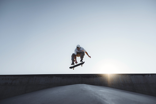 Skater doing kickflip on the ramp at skate park - Stylish skaterboy training outside - Extreme sport life style concept