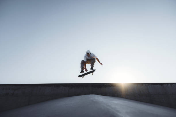 Skater doing kickflip on the ramp at skate park - Stylish skaterboy training outside - Extreme sport life style concept stock photo