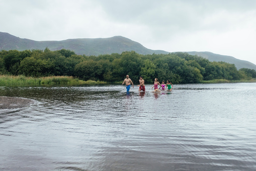 Family open water swimming together in a lake in Keswick, the Lake District. They are on a staycation enjoying time together.