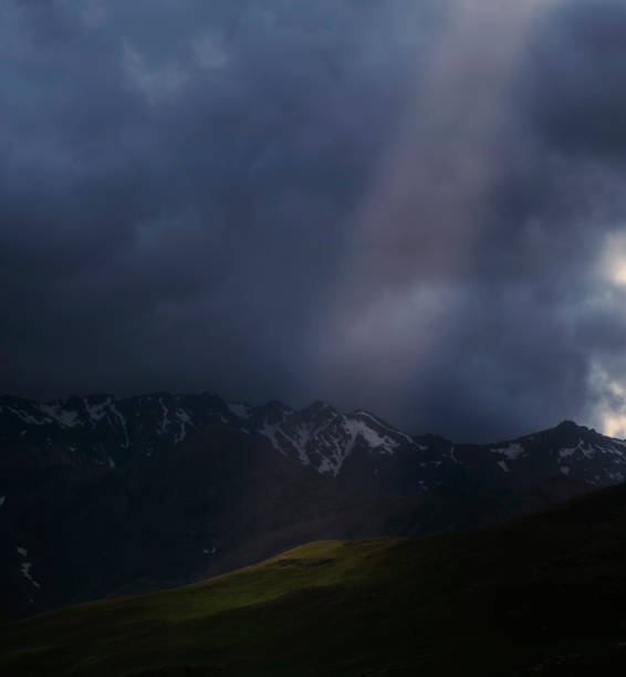 istock Beam of light among dark storm clouds in mountains 1540010783