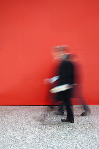istock Two Business People Walking Against a Red Wall, Blurred Motion 154001286