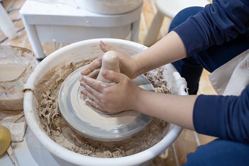 A child is learning to make handmade pottery