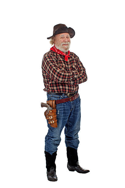 Smiling old cowboy stands with arms crossed Classic old western style smiling cowboy with felt hat, grey whiskers, revolver, stands with arms crossed. Isolated on white background, copy space, vertical. checkered cowboy boots stock pictures, royalty-free photos & images