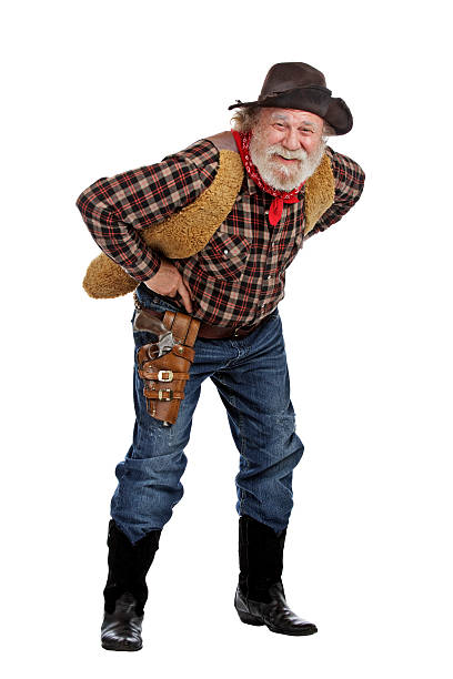 Smiling old cowboy stands leaning forward Classic old west smiling cowboy with felt hat, grey whiskers, revolver, stands bending forward. Isolated on white background, copy space, vertical. checkered cowboy boots stock pictures, royalty-free photos & images