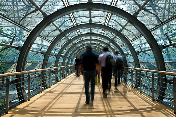 a rear view of people walking across a footbridge, blurred motion