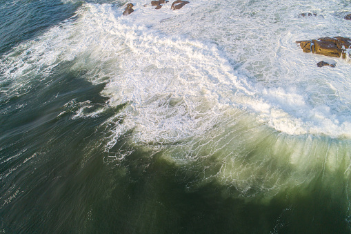 aerial drone view of waves breaking against rocks