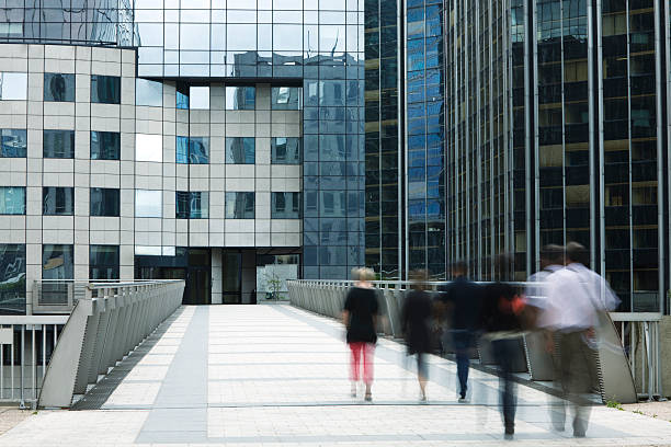 istock Office Workers Walking Down Elevated Walkway Toward Business Building 154003133