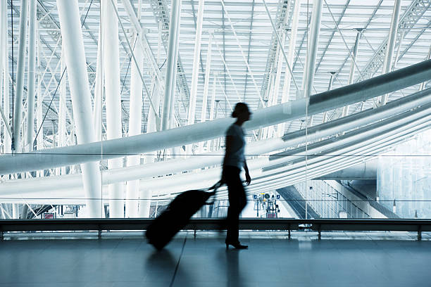 frau ziehen gepäck am flughafen, bewegungsunschärfe, blau getönt - erhöhter fußgängerweg stock-fotos und bilder