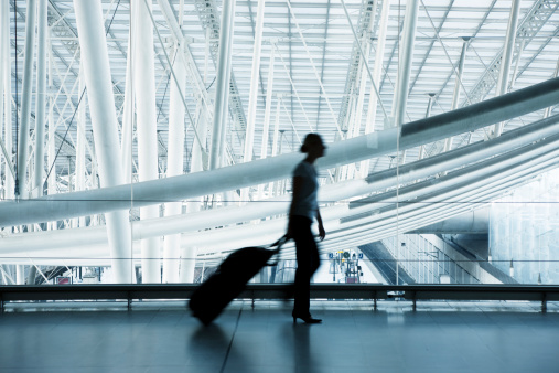Woman Pulling Luggage at Airport, Blurred Motion, Blue Toned Image