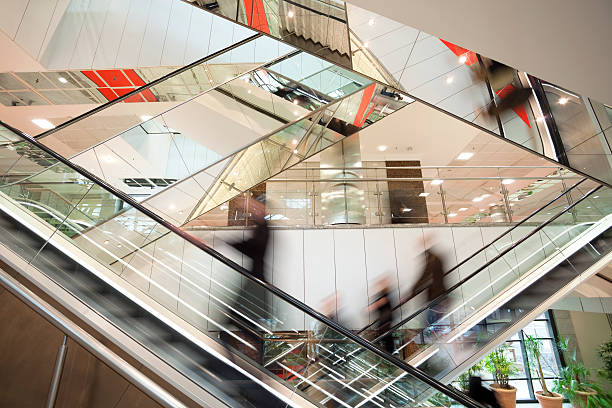 turva as pessoas na escada rolante em vidro moderno interior - escalator people city blurred motion imagens e fotografias de stock