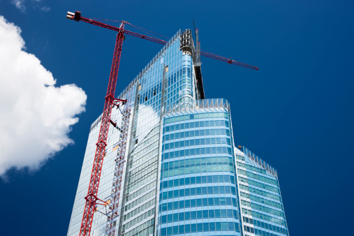 high rise commercial office building in construction stage with huge crane,