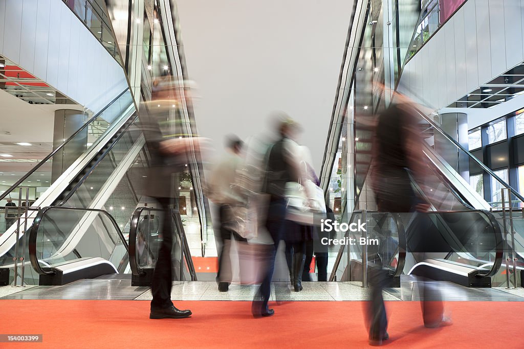 Desfocado pessoas caminhando tapete vermelho para escadas rolantes no Interior moderno - Foto de stock de Shopping center royalty-free