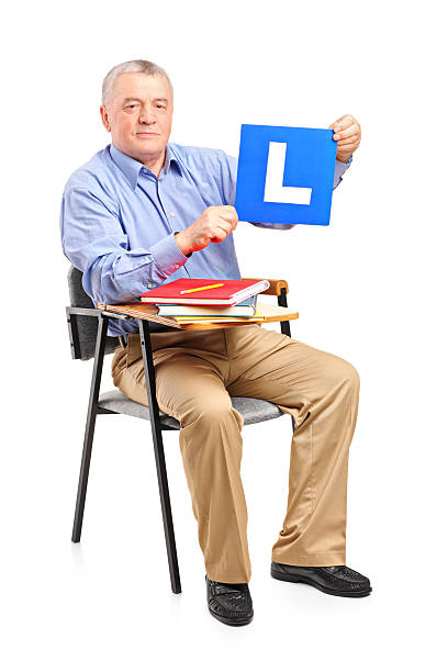 istock Senior man sitting on school chair holding a L plate 154006892