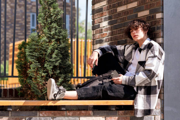 young man sits relaxed on a city bench