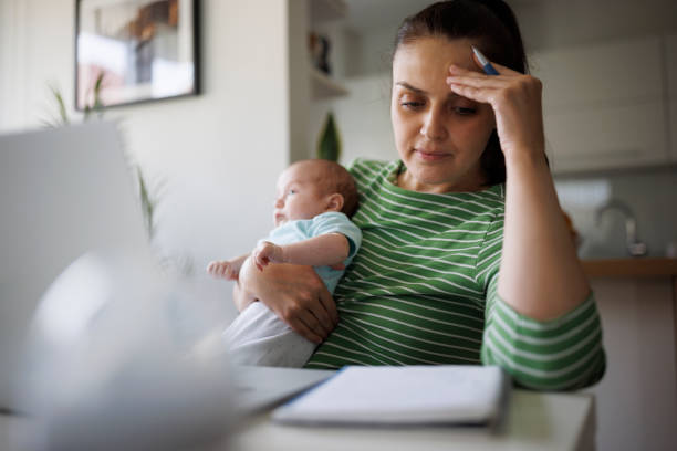Tired and worried mother working at home stock photo