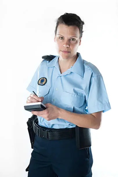 Policewoman standing on white background, writing something on a pad.